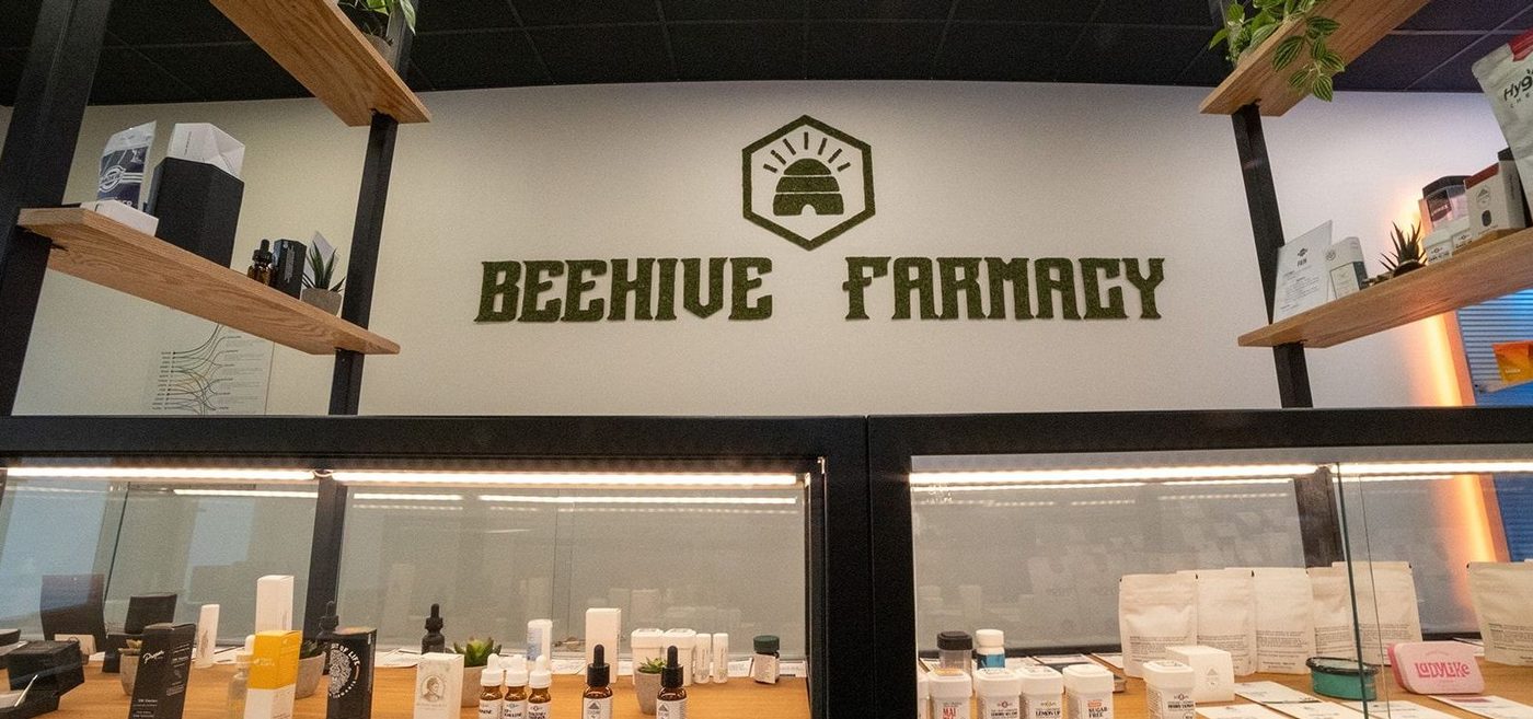 Beehive Farmacy logo on wall above display cases of cannabis products